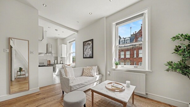 Un apartamento moderno con sala de estar, cocina y un amplio ventanal con vista a la ciudad.