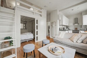 Ein zeitgemäßer, offener Wohnbereich mit Bett, Sofa und Essbereich.