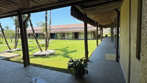 A covered walkway with a view of a grassy area and a building with a tiled roof. - Pousada Village dos Corais  (Matinhos)