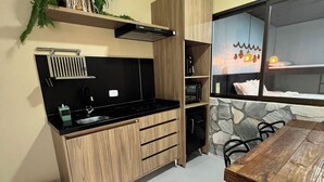 A compact kitchen with a built-in stove, wooden cabinets, and a stone accent wall. - Pousada Village dos Corais  (Matinhos)
