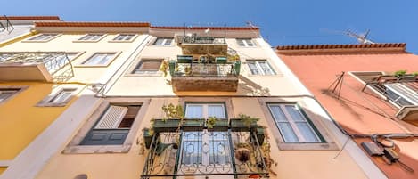 A multi-story building with balconies, windows, and a clear blue sky.