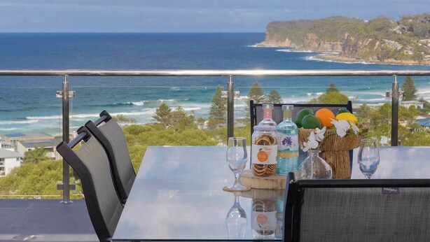 Une table avec vue sur l’océan, une bouteille de spiritueux et un verre.
