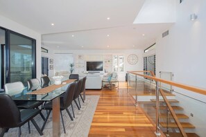 Ein modernes Wohnzimmer mit Essbereich, Küche und Treppe.