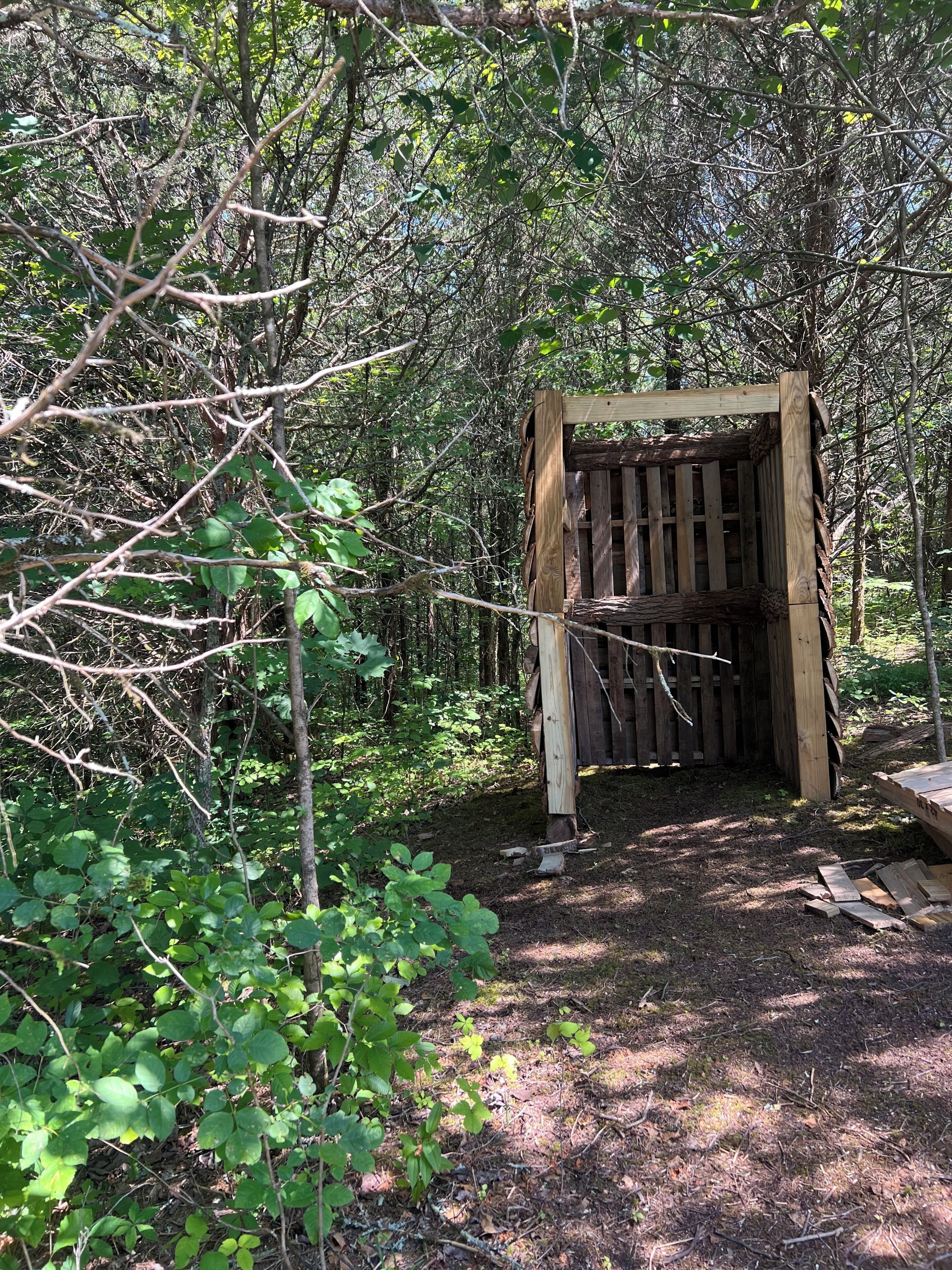 Eine Holzhütte inmitten bewaldetem Gelände mit Erdboden.