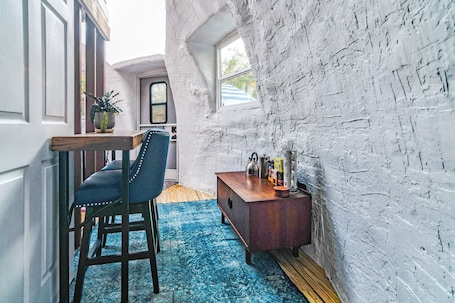A room with a rustic white brick wall, a wooden bench, a blue patterned rug, and a small wooden side table with various items.. Delightful off-grid geodesic dome in charming Greeneville perfect for getaway
