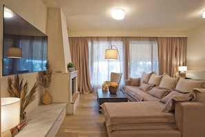 A modern living room with a flat-screen TV, a sofa, a coffee table, and a fireplace. - Holiday Infinity View (Nea Smirni)