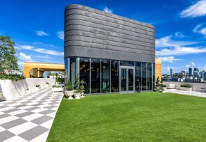 Un edificio moderno con fachada curva, amplios ventanales de vidrio y un piso con patrón a cuadros.