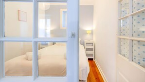 A bedroom with a bed, a nightstand, a lamp, and a window with polka dots. - Historic Typical 1 By Gt House (Lisbon)