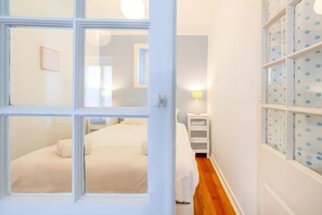 Ein Schlafzimmer mit einem Bett, einem Nachttisch, einer Lampe und einem Fenster mit Punkten.