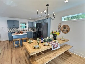Eine moderne Küche mit blauen Schränken, einem schwarzen Kühlschrank und einem Holzespeisetisch, gedeckt mit Tellern und Gläsern.