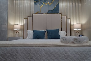 A hotel room with a large bed, two bedside lamps, a wall clock, and a decorative wall piece. -  1-bedroom apartment near The Hard Rock Stadium (Miami Gardens)