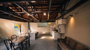 A modern kitchen with a dining area, a bench, and a visible logo on the wall. - Flamboyant Stay Rooms (Goiânia)