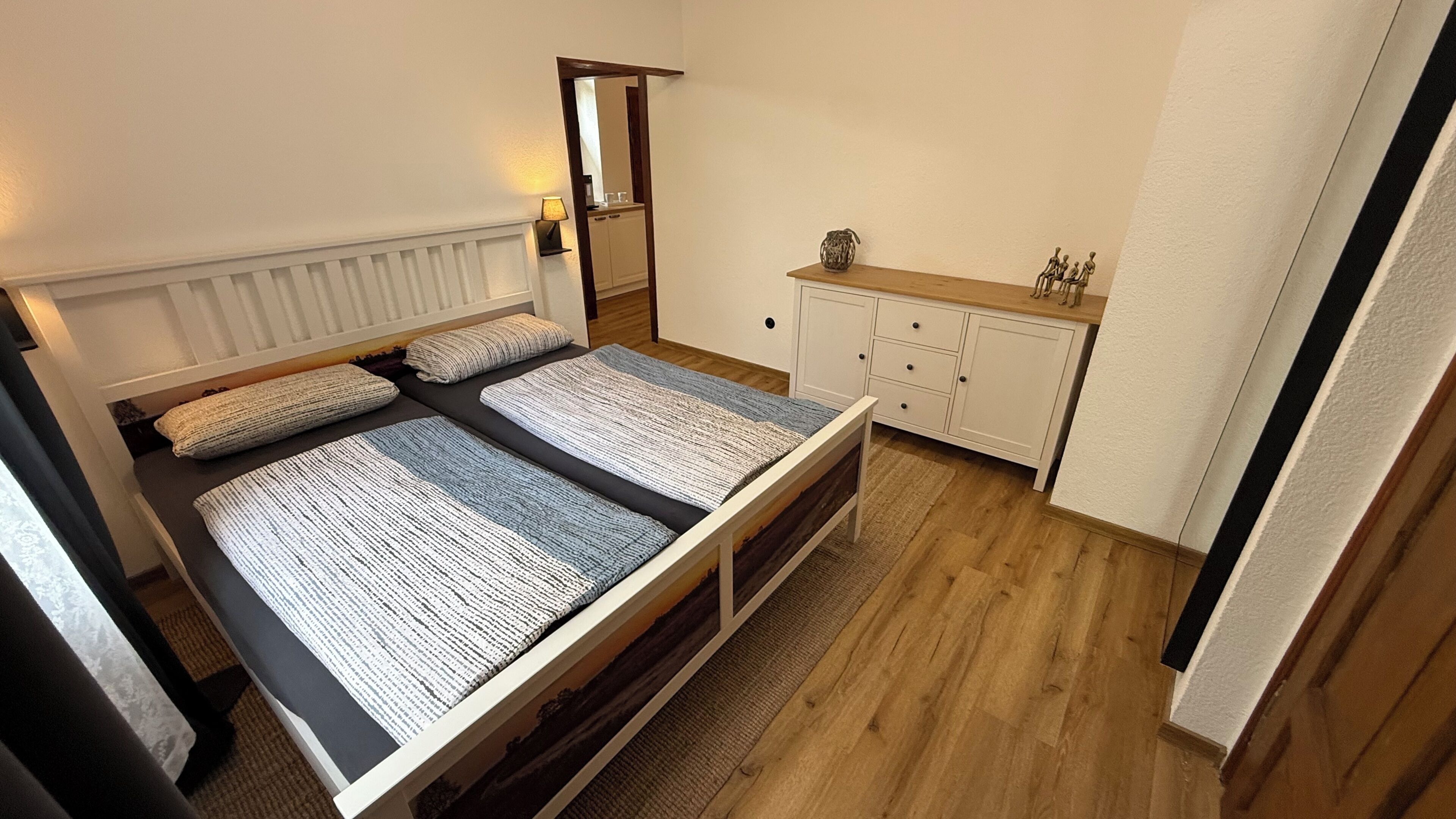 Ein Zimmer mit Bett, Kommode, Spiegel und Heizkörper.