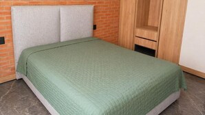 A room with a bed, a brick wall, and a wooden wardrobe. - LUUM 202 (Guadalajara)