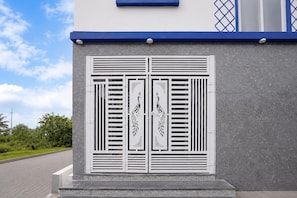 A building facade with a textured gray wall and a blue trim at the top. - Classic Airport Stay (Nelamangala)
