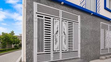 A building facade with decorative metal shutters, a blue trim, and a textured wall.