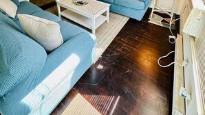 A living room with a blue sofa set, a white coffee table, a hanging lamp, and a fireplace. - Classic Downtown OC Beach Cottage. Walk Everywhere (Ocean City)