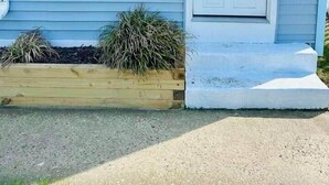 A house with a front door, two windows, a small porch, and a wooden planter with plants. - Classic Downtown OC Beach Cottage. Walk Everywhere (Ocean City)
