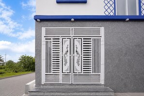 A building facade with a textured gray wall and a blue trim at the top.