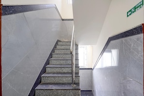 Un escalier avec des marches et des rampes en marbre, menant à une sortie.