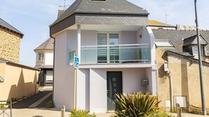 A two-story building with a balcony, a small window on the upper floor, and a door with a modern design. - Townhouse with garage, Saint-Quay-Portrieux (Saint-Quay-Portrieux)