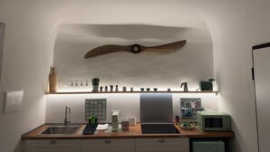 Et køkken med en træloftsventilator, en indbygget hylde med planter, en mikroovn og en kaffemaskine.