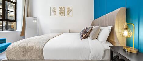 Une chambre à coucher moderne avec un lit, une table de chevet et une œuvre d’art accrochée au mur.