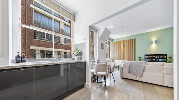 A modern kitchen with a large window, a dining area with a sofa, and a flat-screen TV. - 3 -Berry Street EC1V (London)