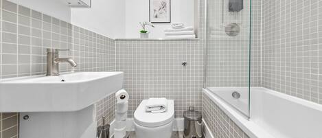 A modern bathroom with a sink, toilet, and bathtub.