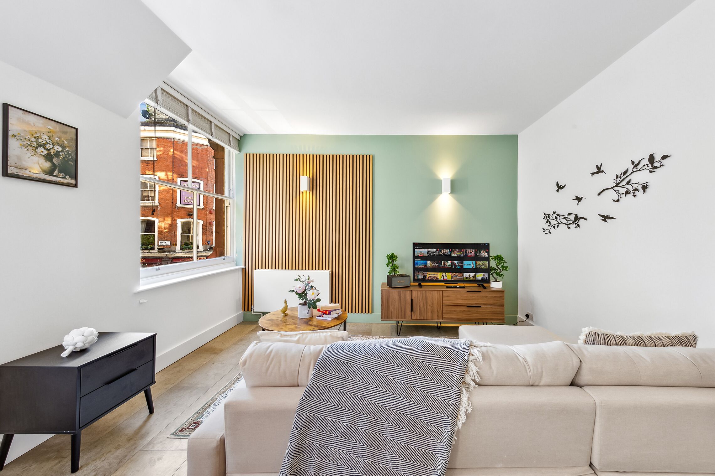 Een moderne woonkamer met een bank, een klein tafeltje, een televisie en een wandpaneel van hout.
