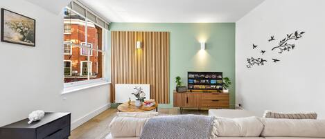 Een moderne woonkamer met een bank, een klein tafeltje, een televisie en een wandpaneel van hout.