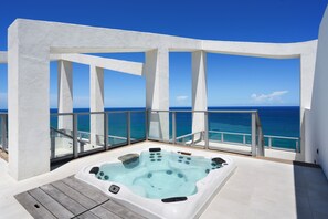 Un jacuzzi en un balcón con vista despejada al océano.
