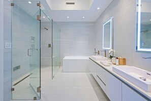 Un baño moderno con cabina de ducha de vidrio, una bañera independiente y un tocador con espejo.