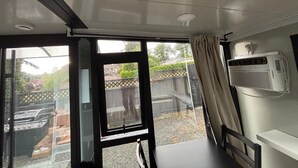Een kamer met een schuifdeur naar een achtertuin, een plafondventilator en een airconditioner aan de muur.
