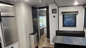 Interior compacto de una caravana con cocina americana, zona de estar y una pequeña ventana.