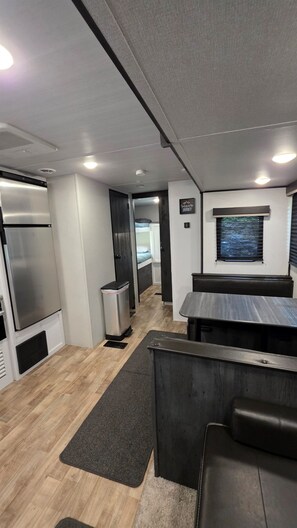 Interior compacto de autocaravana con kitchenette, zona de estar y una ventana pequeña.