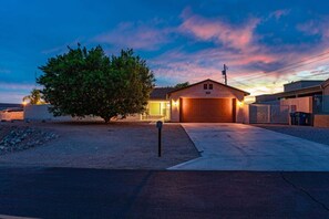 A residential house with a garage, driveway, and a tree in the front yard. - Highlander Retreat - Pool, Pool Table, Comfort (Lake Havasu City)