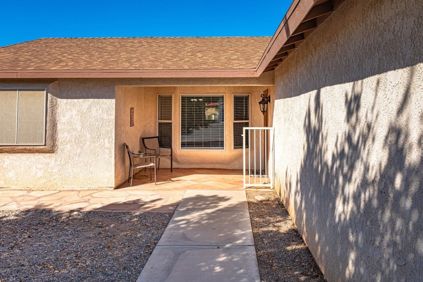 A residential property with a covered patio, a garage, and a small outdoor seating area.
