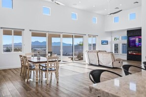 A spacious room with a dining area, a sofa, and a TV. - Luxury Cardinal Retreat - Pool, Spa, BBQ, Garage (Lake Havasu City)