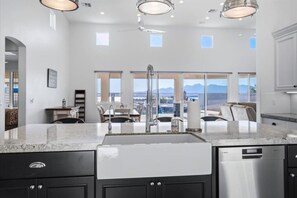 A modern kitchen with a large island, stainless steel appliances, and a view of mountains through large windows. - Luxury Cardinal Retreat - Pool, Spa, BBQ, Garage (Lake Havasu City)
