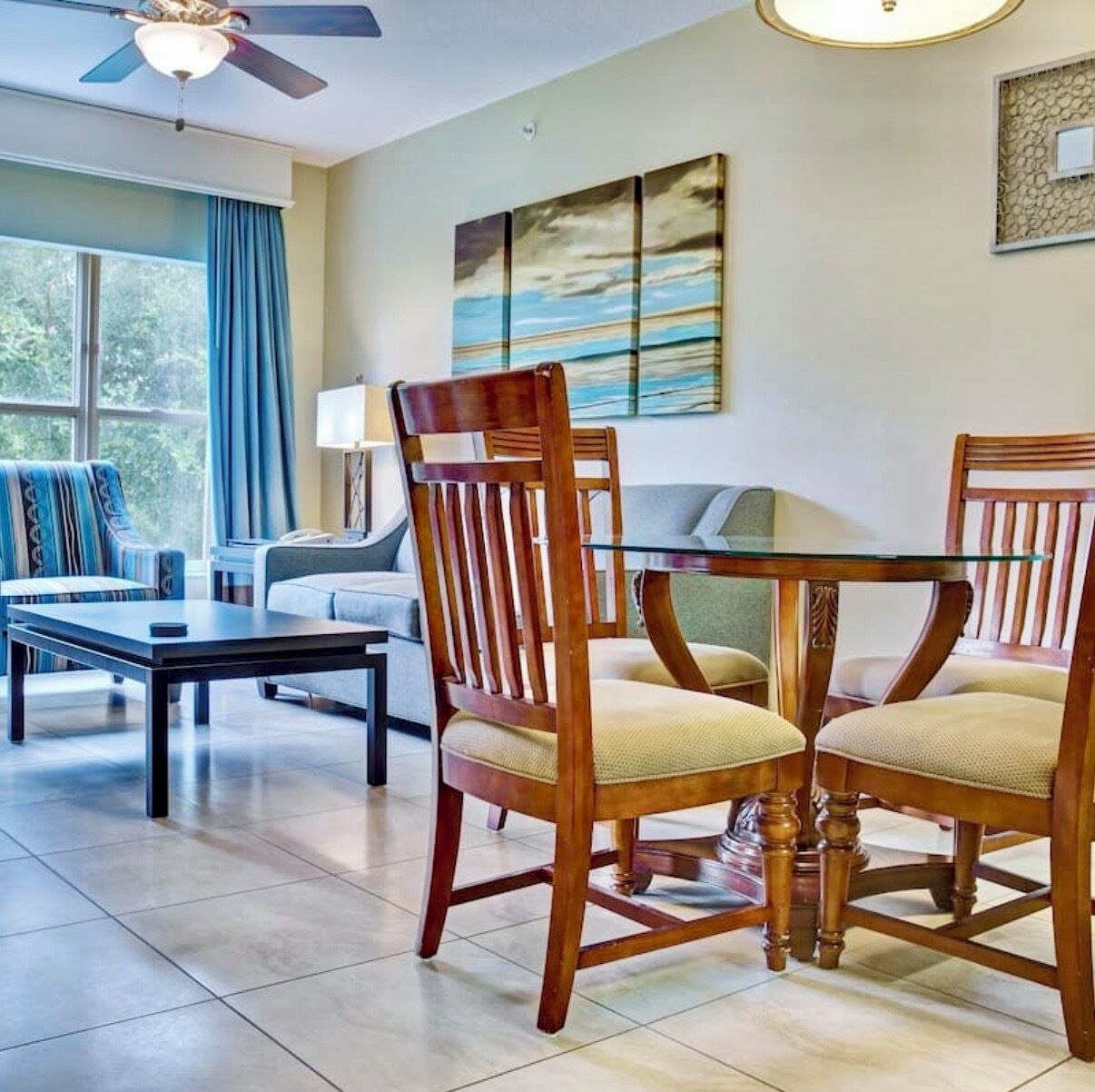 Un coin repas avec une table en verre, des chaises en bois, un canapé et un tableau accroché au mur.