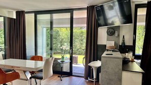 A modern kitchen with a flat-screen TV, a clock, and a small bar area. - Azúr Port Siófok Balaton - Hungary (Siófok)