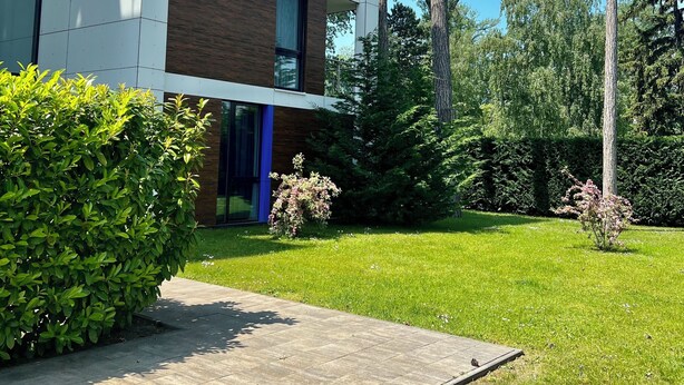A modern building with a glass facade, a wooden exterior, and a well-maintained lawn with trees. - Azúr Port Siófok Balaton - Hungary (Siófok)