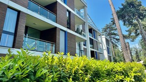 A multi-story building with balconies, large windows, and a surrounding green landscape. - Azúr Port Siófok Balaton - Hungary (Siófok)