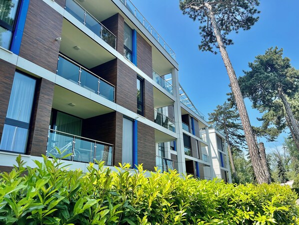 A multi-story building with balconies, large windows, and a clear sky.
