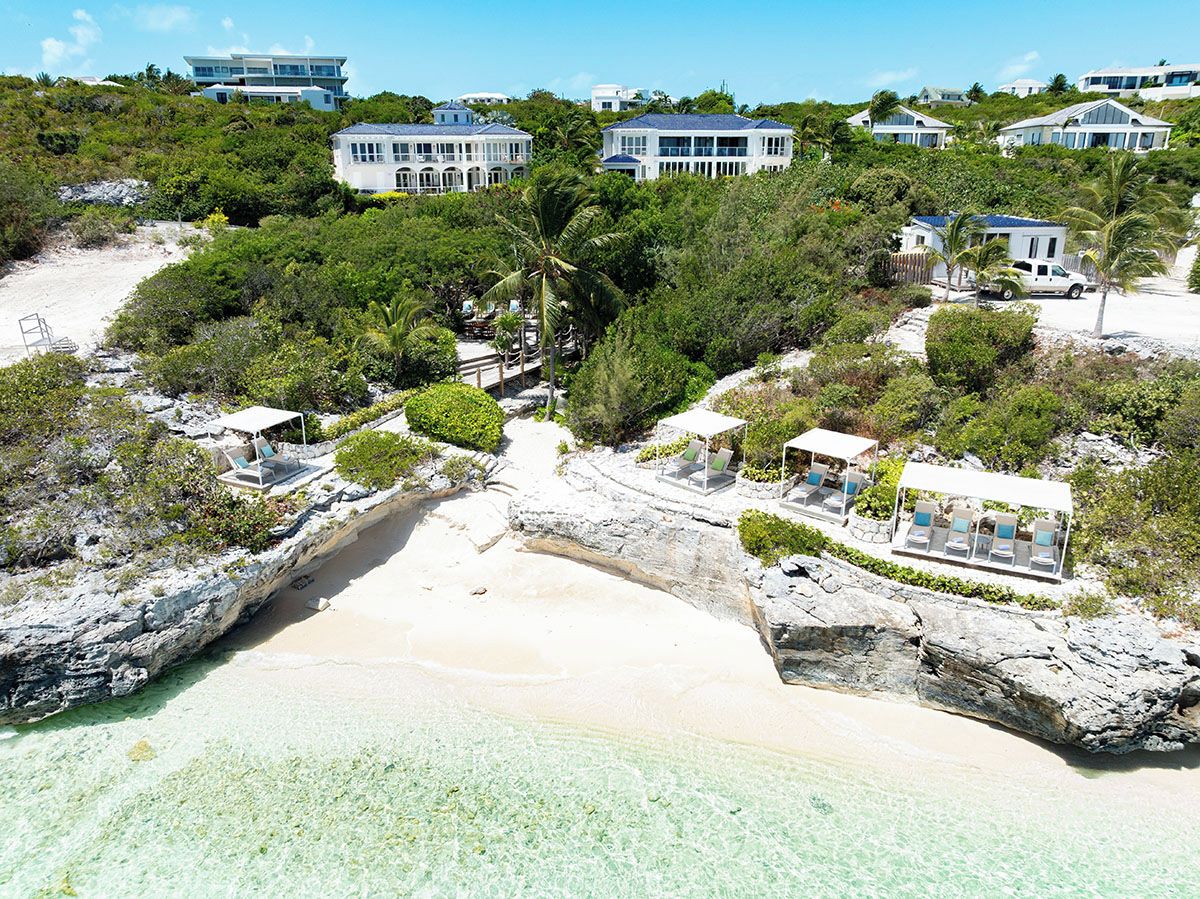 Une propriété située sur la côte, avec une plage, plusieurs maisons et une vue dégagée sur l’océan.