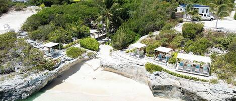 A coastal property with a beach, multiple houses, and a clear view of the ocean.