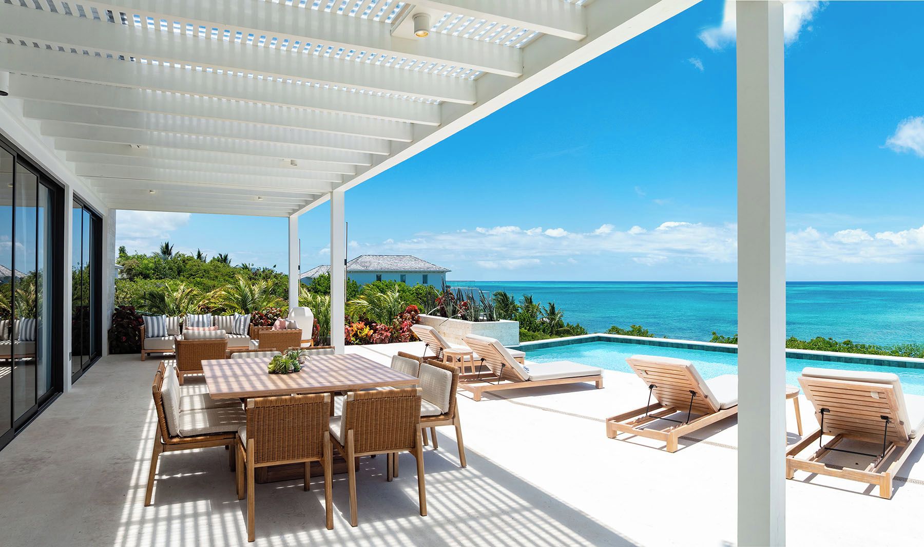An outdoor patio with a pool, lounge chairs, and a dining area with a table and chairs.