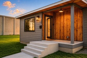 Una casa moderna con una porta d'ingresso in legno, un piccolo portico e una scala di cemento che conduce all'ingresso.