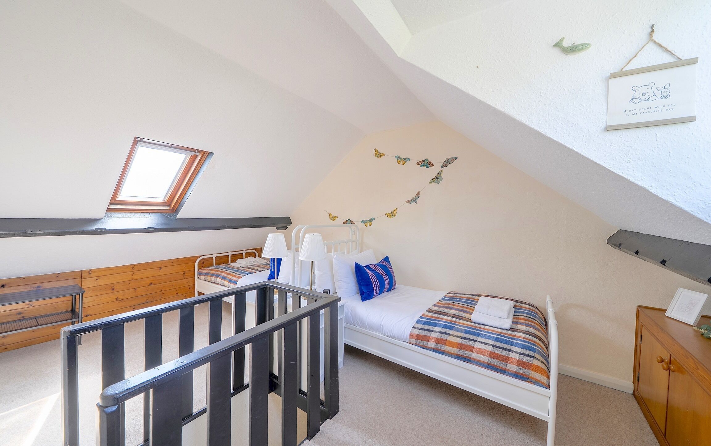 Un dormitorio con techo inclinado, una cama con manta escocesa, un banco de madera y una mesita.